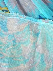 Macro shot of sky blue pleated chiffon fabric with ruffled edges and printed patterns