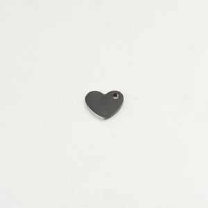 Polished black heart-shaped stainless steel pendant on a white marble background