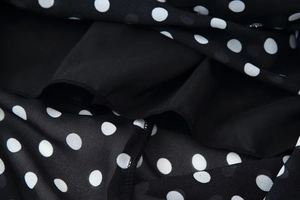 Detail of black polka dot printed fabric with lightweight layered lining and fine stitching
