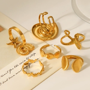 Set of 6 gold seashell and starfish ocean-themed rings on vintage beige script paper