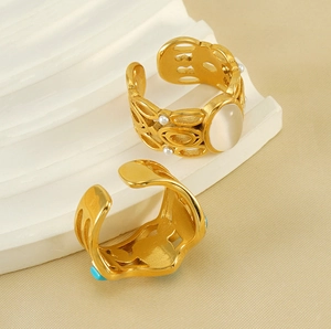 Close-up of gold-plated rings featuring white opal, pearl, and blue turquoise details