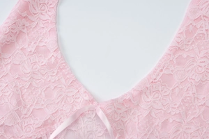 Close-up of pink lace V-neck top featuring delicate floral texture and a ribbon bow