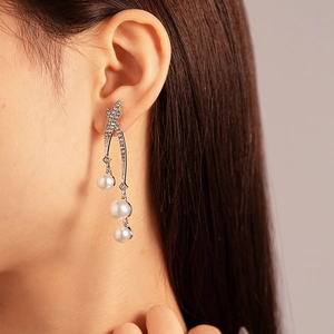 Detail of silver drop earrings with sparkling rhinestones and white cascading pearls