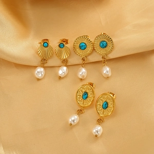 Bohemian gold plated earrings set with turquoise and pearls on champagne satin fabric
