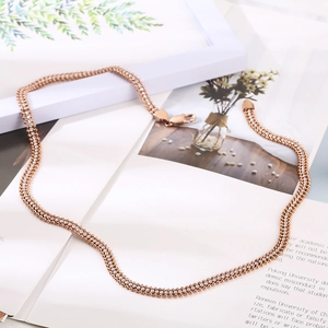 Dettaglio di una collana a doppio strato in oro rosa con strass su sfondo di rivista