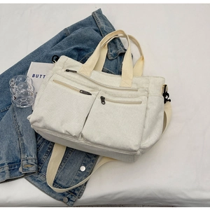 Detail of white corduroy tote bag with dual front pockets and adjustable straps