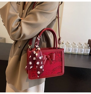 Detail of red wedding handbag with floral embroidery, large bow and silk scarf handle