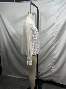 Détail de la chemise blanche en satin à manches longues avec design tissé sur un mannequin