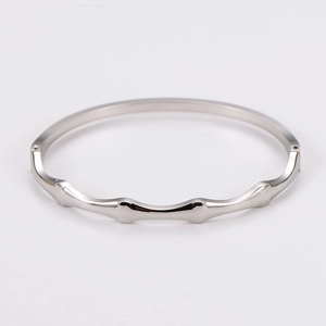 Close-up of a silver stainless steel bangle with a minimalist wavy bamboo joint design
