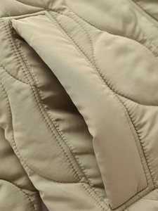 Detail view of khaki quilted outerwear showing fine stitching and side pocket texture