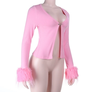 Détail du cardigan rose avec poignets en plumes synthétiques et boucle en métal