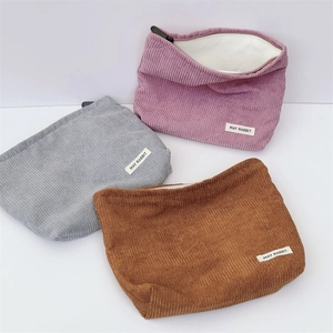 Close-up of corduroy makeup bags in pink, grey and brown showing velvet texture and zippers