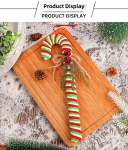 Close-up of knit Christmas candy cane with pine needles and bells on wooden tray