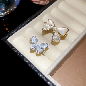 Close-up of 14k gold plated bow and silver butterfly rings on a beige velvet box