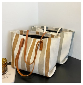 Detail of woven canvas tote bag with vertical stripes and leather texture handles