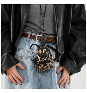 Close-up of leopard print mini bag charm with adjustable lanyard worn on model's chest
