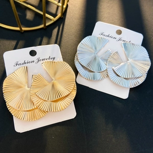 Detailed view of large fan-shaped pleated earrings in gold and silver finish