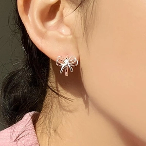 Close-up of 925 sterling silver butterfly ribbon earrings worn on model's ear