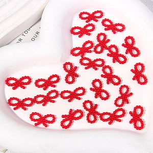 Detailed view of red pearl bead bowknot charms for DIY phone case crafts and decor
