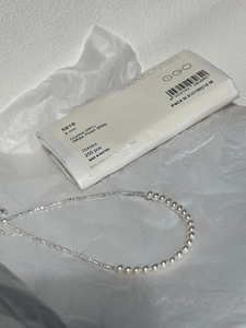 Elegant 8mm white pearl and silver chain necklace displayed on minimalist white art paper