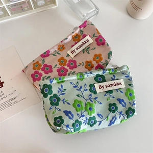 Flat lay of small floral fabric pouches with zipper and By sozakka brand label