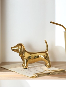 Close-up of golden ceramic dachshund statue on clipboard with handwritten letter