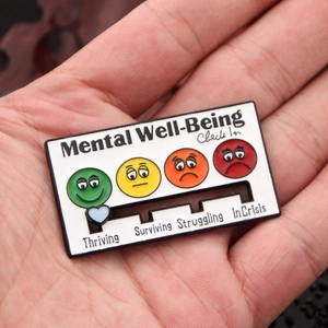 Macro view of a sliding mental health check-in pin with enamel emoji indicators
