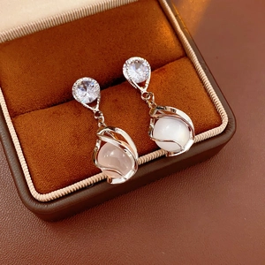 Detail of silver drop earrings with opal beads inside a brown velvet jewelry box