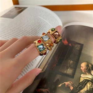 Vintage gold-tone ring set with square colored gemstones and hammered texture on hand