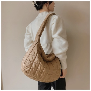Close-up of khaki quilted padded shoulder bag styled on model with white sweater