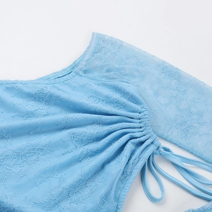 Dettaglio del tessuto in pizzo azzurro con motivi floreali e coulisse laterale regolabile