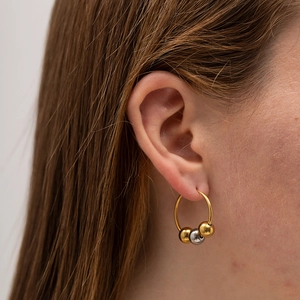 Detail shot of a gold hoop earring with mixed gold and silver beads on a model's ear