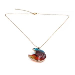 Détail du pendentif lune avec dégradé rouge et bleu sur une chaîne dorée