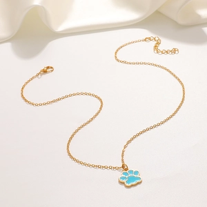 Close-up of gold chain necklace with a light blue enamel paw print pendant on white silk