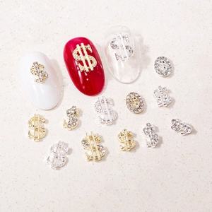 Detailed close-up of gold and silver dollar sign nail art charms with rhinestone accents