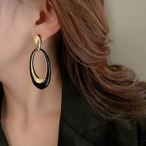 Close-up of vintage black enamel layered oval drop earrings worn on a model
