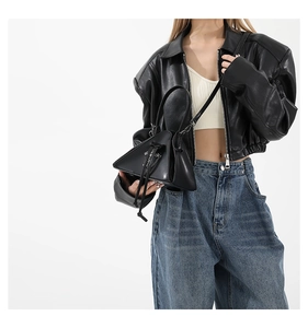 Detail of a chic black punk-style triangular crossbody bag styled with a leather jacket