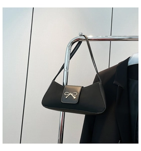 Detailed view of black PU leather baguette bag with a silver metallic bow decoration