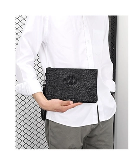 Detail of black embossed crocodile pattern men's clutch bag with wristlet strap