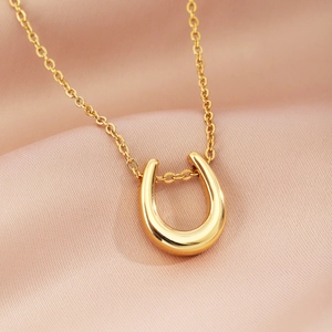 Elegant gold U-shape horseshoe necklace on soft pink silk background