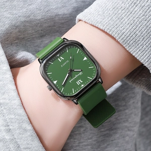 Square quartz watch with green dial and matching silicone strap on a female wrist
