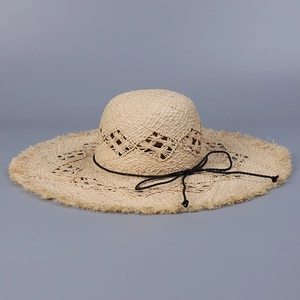 Detail of hand-woven raffia sun hat with hollow diamond patterns and frayed wide brim