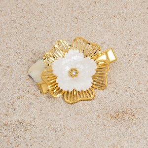 Detailed macro view of a golden hollow flower hair clip with pearl shell petals and zircon