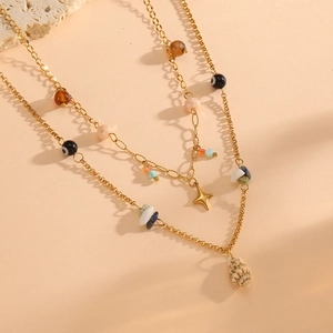 Detailed view of layered gold necklace with shell and devil's eye pendants