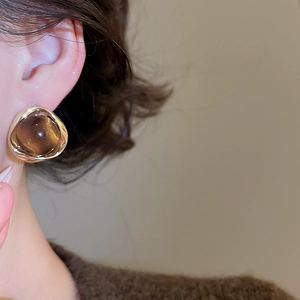 Detail of 18k gold plated earring with brown tiger eye stone on model's ear