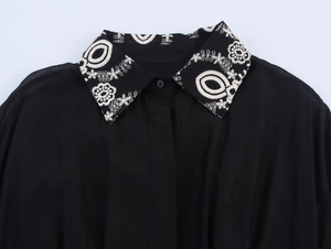 Close-up of the elegant lapel collar featuring white floral embroidery on a black dress