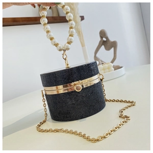 Detail of cylinder evening bag featuring black rhinestones and pearl handle with gold chain