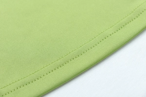 Detailed close-up of double-stitched hem on a light green athletic yoga jacket