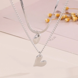 Detail of silver double-layered heart pendant necklace with snake and O-chain texture