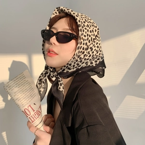 Polka dot silk scarf worn by model in sunset light with fashionable glasses and newspaper